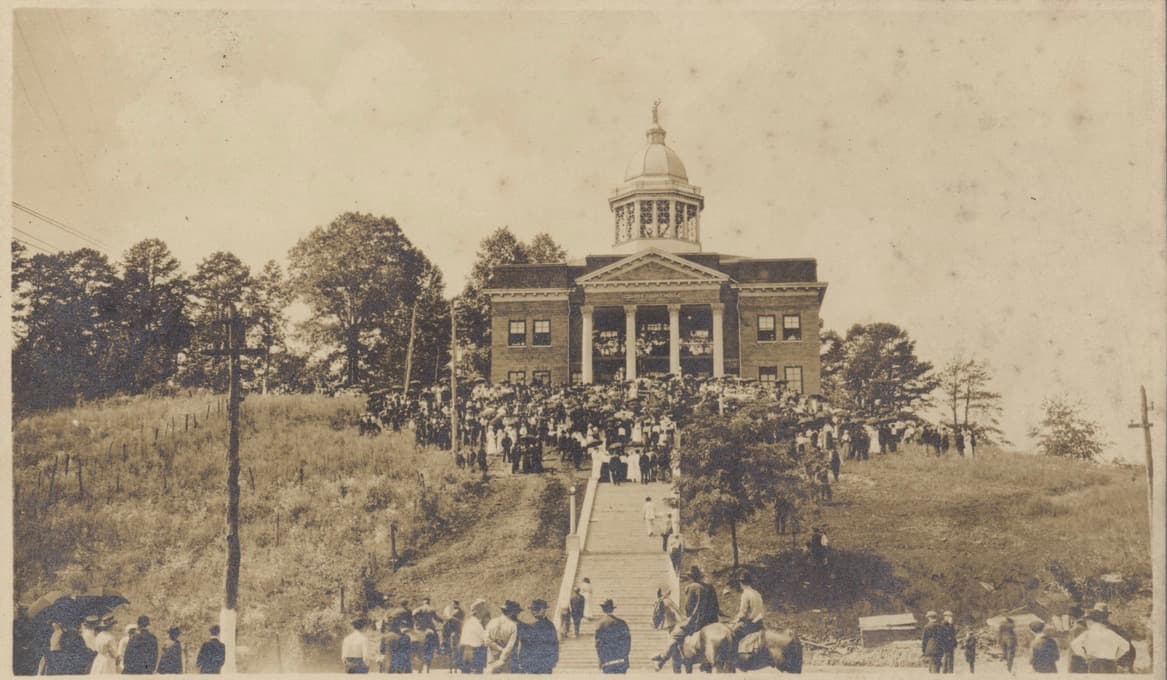 Sepia-toned historic photograph of the Jackson County Courthouse, a domed building on a hill, with a large crowd gathered on the lawn and stairs for a dedication or public ceremony.